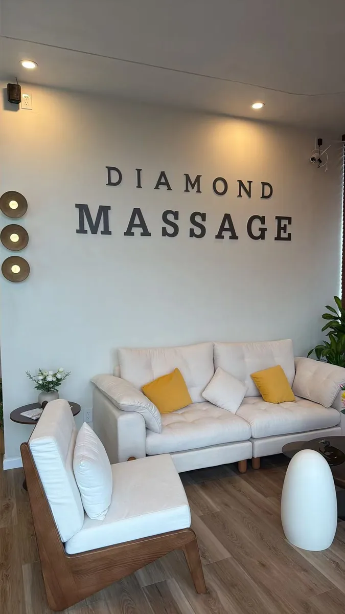 The lounge at Diamond Massage, DIAMOND MASSAGE lettering on the wall above a cream sofa with mustard cushions