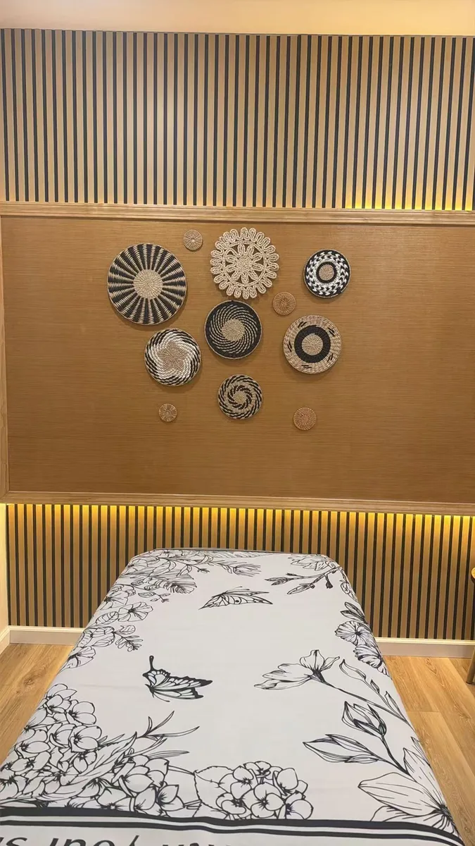 treatment room at Diamond Massage with woven basket wall art above a draped table